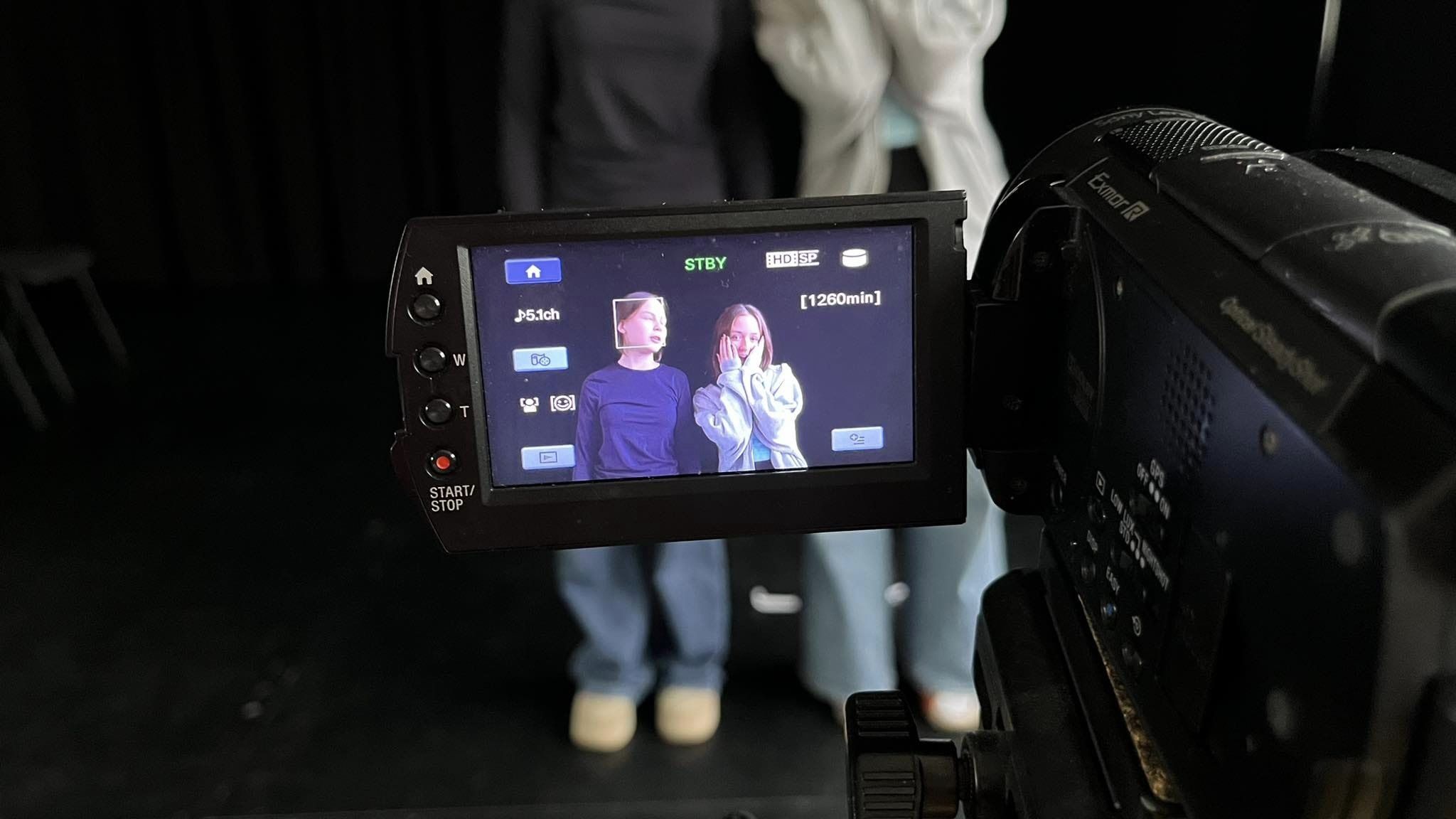 Kamera, na której ekranie widać dwie nastolatki. Jedna ma spięte blond włosy i granatową bluzkę, druga - rozpuszczone włosy i szarą bluzę.